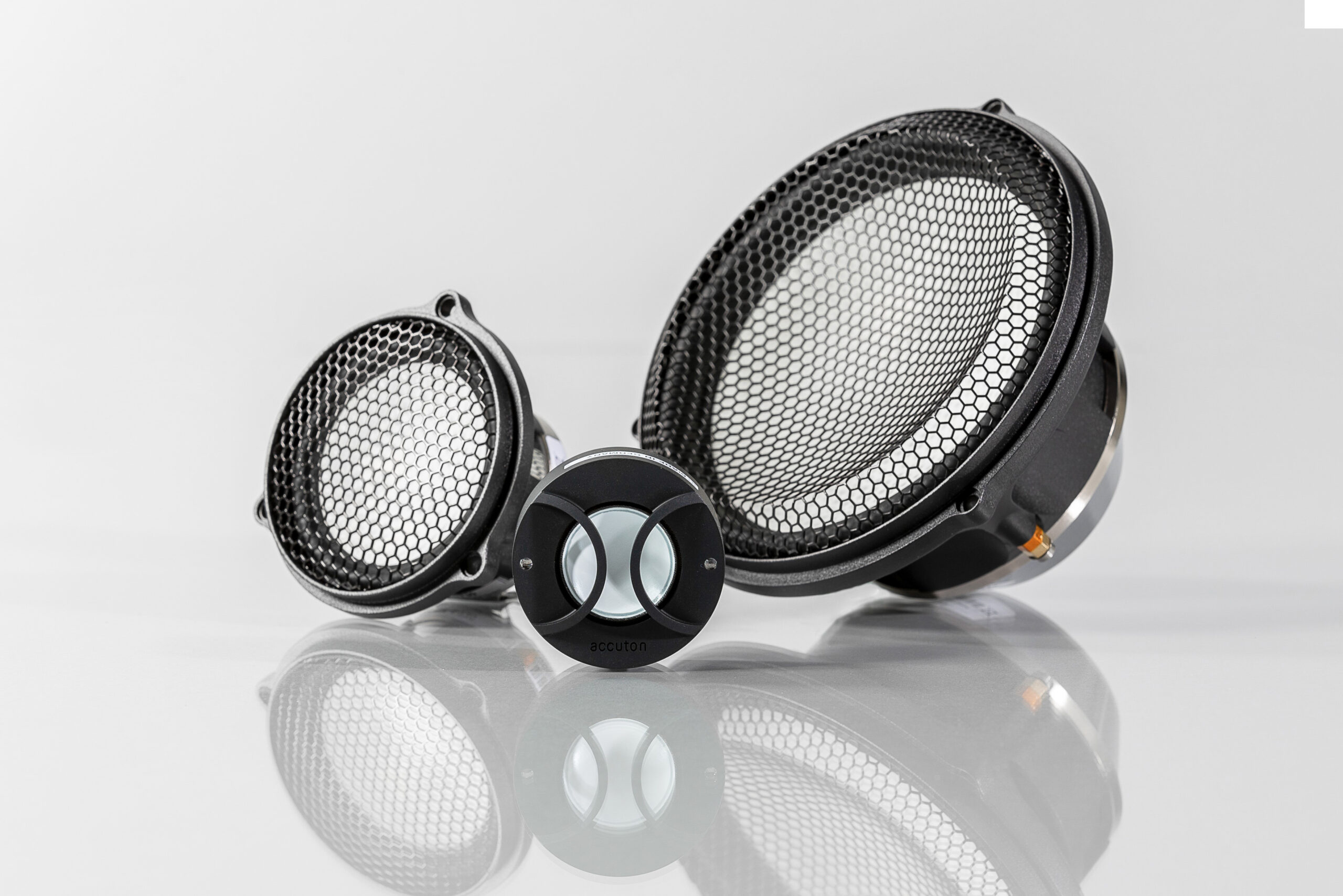 Three Accuton Automotive loudspeakers and their reflections on a polished surface.